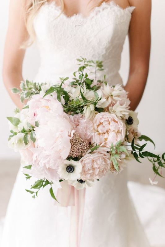 a refined and subtle wedding bouquet of light pink blooms, white anemones, greenery and berries is a chic idea for spring
