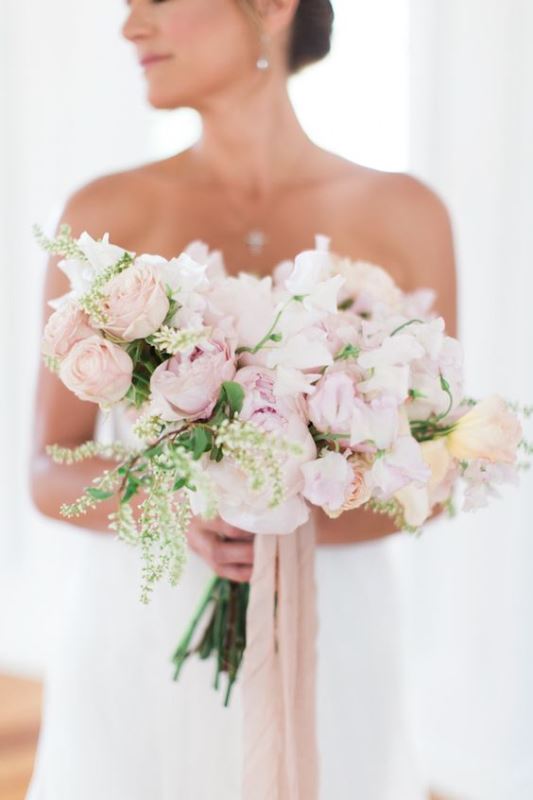 a sophisticated wedding bouquet of light pink and white blooms, greenery and long blush ribbons is a very beautiful accessory