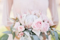 a subtle wedding bouquet of light pink roses and a king protea plus greenery is a gorgeous statement for a spring or summer wedding