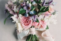 a beautiful fine art wedding bouquet with blush and white peony roses, white and purple blooms and ribbons is a lovely solution for a spring or summer wedding