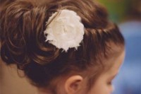 a messy updo with braids on both sides of the head and a single white bloom is lovely and easy idea for a less formal wedding