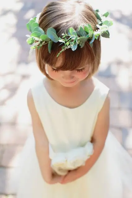 simple natural hair down with a fringe and a greenery crown are all your flower girl needs to look amazing