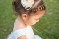 a messy updo with a braided halo and additoinal silk flowers and pearls to accent the look