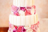 a bold wedding cake with textural white tiers and bright pink blooms between the tiers
