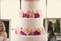 a white patterned wedding cake with blush and fuchsia blooms between the tiers is a bright and chic idea