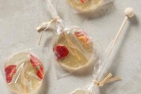 clear round lollipops with pieces of strawberry inside are a cool idea for any summer wedding, such easy favors can be DIYed