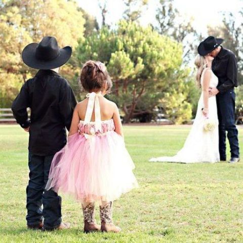 a pink strapless tulle knee dress with brown cowboy boots is a look inspired by the bride's outfit