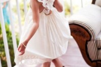 a white knee dress with a lace criss-cross back, no sleeves, cowboy boots and a updo with a fabric flower for a summer rustic wedding