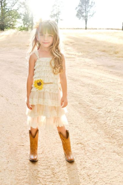 a white lace ruffle knee dress with thick straps, cowboy boots and a small sunflower to highlight the look of the girl