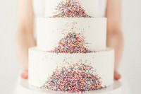 a large white wedding cake decorated with colrful sprinkles is a lovely and bold idea for a touch of fun