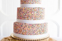 a colorful sprinkle wedding cake with white ribbons is a chic idea for a disco themed wedding, add disco balls to it