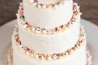 a white wedding cake with textural edges and colorful sprinkles is a lovely idea for a touch of whimsy on the dessert table