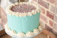 a mint-colored wedding cake with sugar patterns and sprinkles on top plus a pink sprinkle heart topper