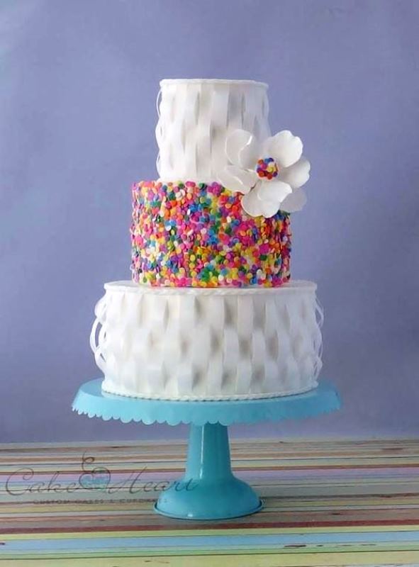 a bold wedding cake with woven tiers and a sprinkle one in the center plus a sugar bloom with sprinkles is wow