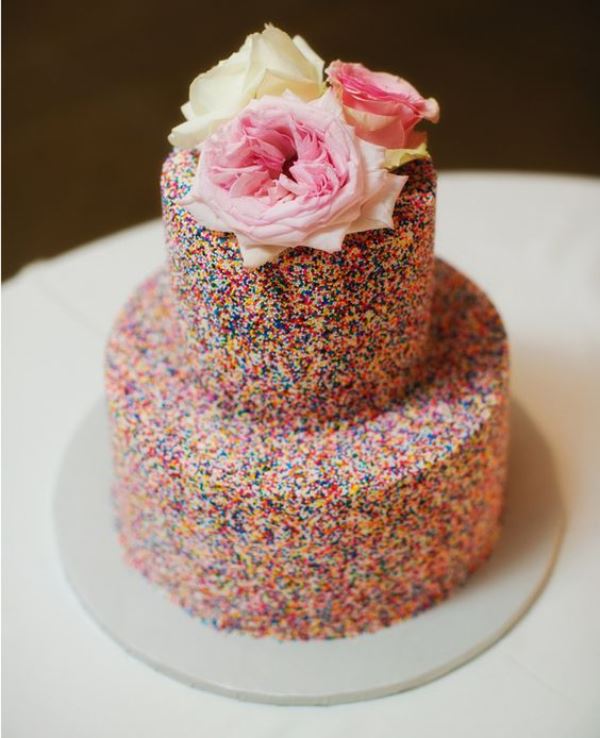 a two-tier sprinkle wedding cake topped with pink and white blooms is a lovely idea for a modern whimsy wedding