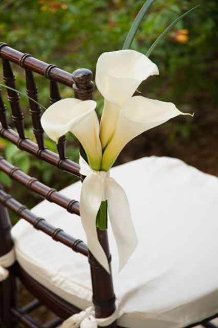 a white calla lily arrangement attached to the chair is a beautiful idea to accent your wedding aisle and isn't difficult to make