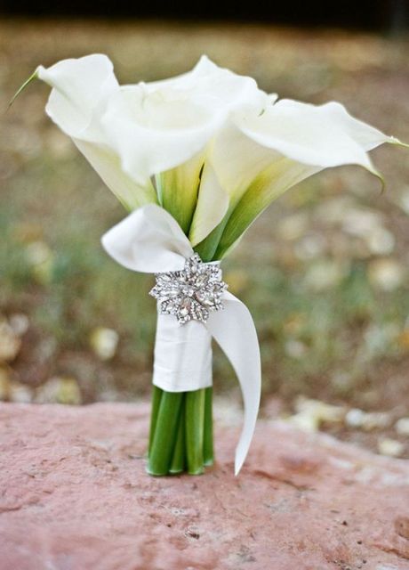 a white calla lily wedding bouquet with a ribbon wrap and a vintage brooch is a chic and stylish idea for a bride