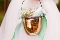 a copper jar used as a basket with green bows and baby’s breath is a unique take on a traditional piece