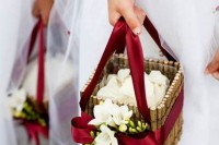 a stick flower girl basket decorated with burgundy ribbons and white blooms