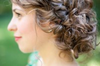 a curly updo with a low bun and a braided halo is a chic hairstyle that will last all day long