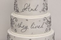 a white wedding cake decorated with grey decor and quotes and pearls for a Disney themed wedding