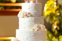a white textural wedding cake decorated with fresh blooms and a Mickey and Minnie Mouse topper