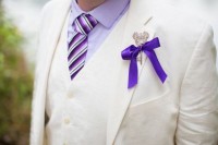 a creamy three-piece suit, a lavender shirt, a striped tie, a Mickey Mouse themed key boutonniere with a bow