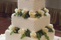 a white square wedding cake with beading and fresh white blooms plus greenery