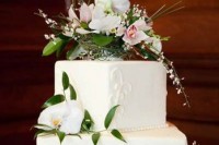a white textural wedding cake topped with fresh bblooms and greenery