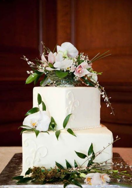 a white textural wedding cake topped with fresh bblooms and greenery
