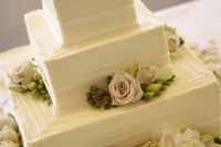 a white textural wedding cake topped with fresh blooms, berries and greenery