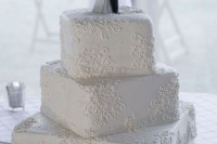 a white patterned wedding cake with a cute figurine cake topper is a very old school idea