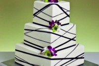 a white square wedding cake decorated with black ribbons and bright purple orchids