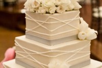 a square wedding cake with patterns, grey ribbons and fresh blooms