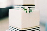a white square wedding cake with striped black and white ribbons and small white flowers