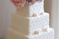 a white formal wedding cake with textural sides and fresh blooms on top