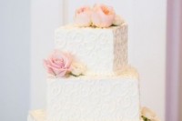 a textural white square wedding cake topped with blush blooms for an elegant wedding
