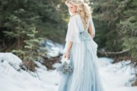 Cinderella bridal look with a layered white and blue wedding gown with a train and short sleeves for a winter wedding