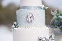 a Frozen themed wedding cake in white and light blue with a touch of glitter pplus rhinestones and embellishments