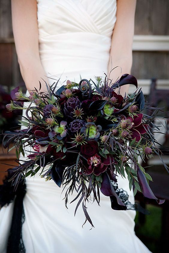 a Halloween wedding bouquet of deep purple callas, burgundy roses and orchids, greenery, berries and textural foliage