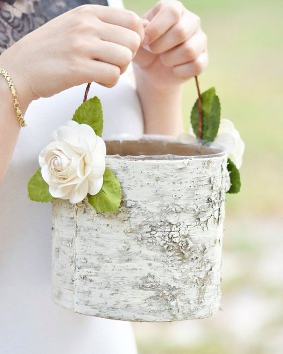 a basket made of tree bark and decorated with fabric blooms and greenery is a nice fit for a rustic wedding