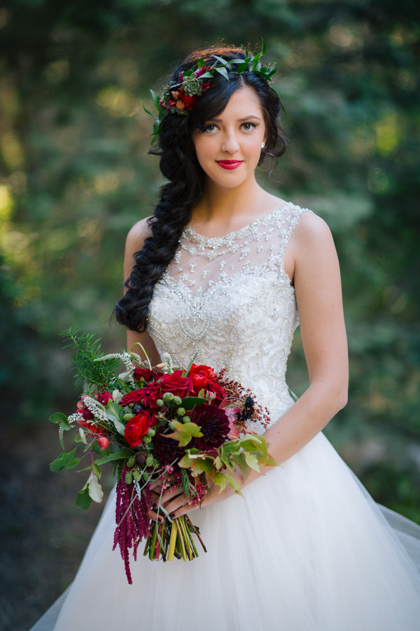 a beautiful Snow White bridal look with an embellished ballgown, a long braid with a floral and greenery crown plus a bold bouquet