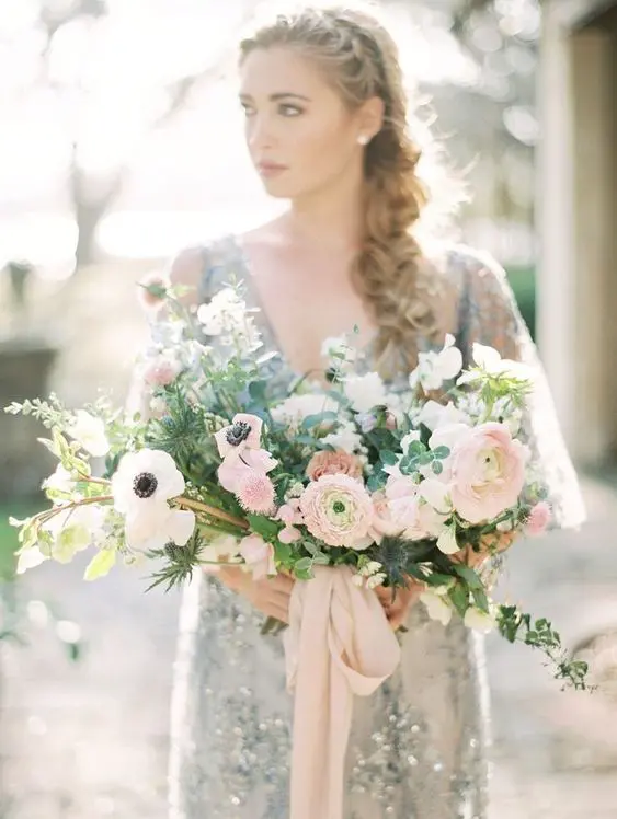 a beautiful and dimensional pink wedding bouquet with white anemones, blush ranunculus, greenery and branches is amazing for a spring wedding