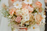 a beautiful textural wedding bouquet of orange and pink roses and ranunculus, white blooms and greenery plus dried foliage