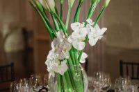a beautiful wedding centerpiece of white orchids and calla lilies surrounded with candles is a chic idea for any wedding