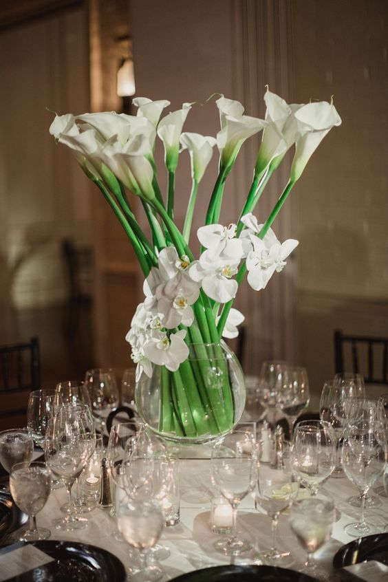 a beautiful wedding centerpiece of white orchids and calla lilies surrounded with candles is a chic idea for any wedding