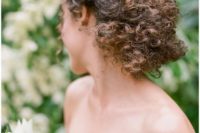 a braided low updo with natural curls is a chic textural idea that will make a statement in your look