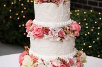 a chic white textural wedding cake with bright pink blooms and berries and a cute topper is wow