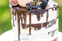 a chocolate drip naked wedding cake topped with macarons and fruit looks incredibly yummy and super delicious