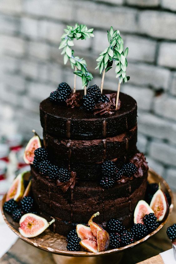 a chocolate naked wedding cake with blackberries, figs and greenery is a great choice for a fall wedding with a boho feel
